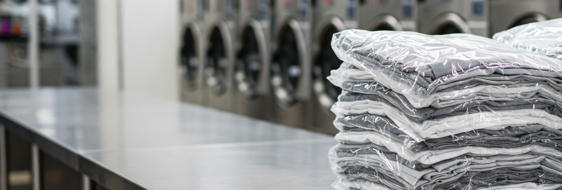 Folding Table With Folded Clothes Wrapped In Plastic 1920X650